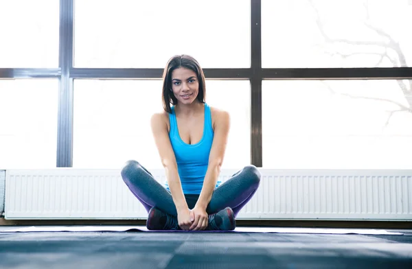 Jonge mooie vrouw zitten op yoga mat — Stockfoto