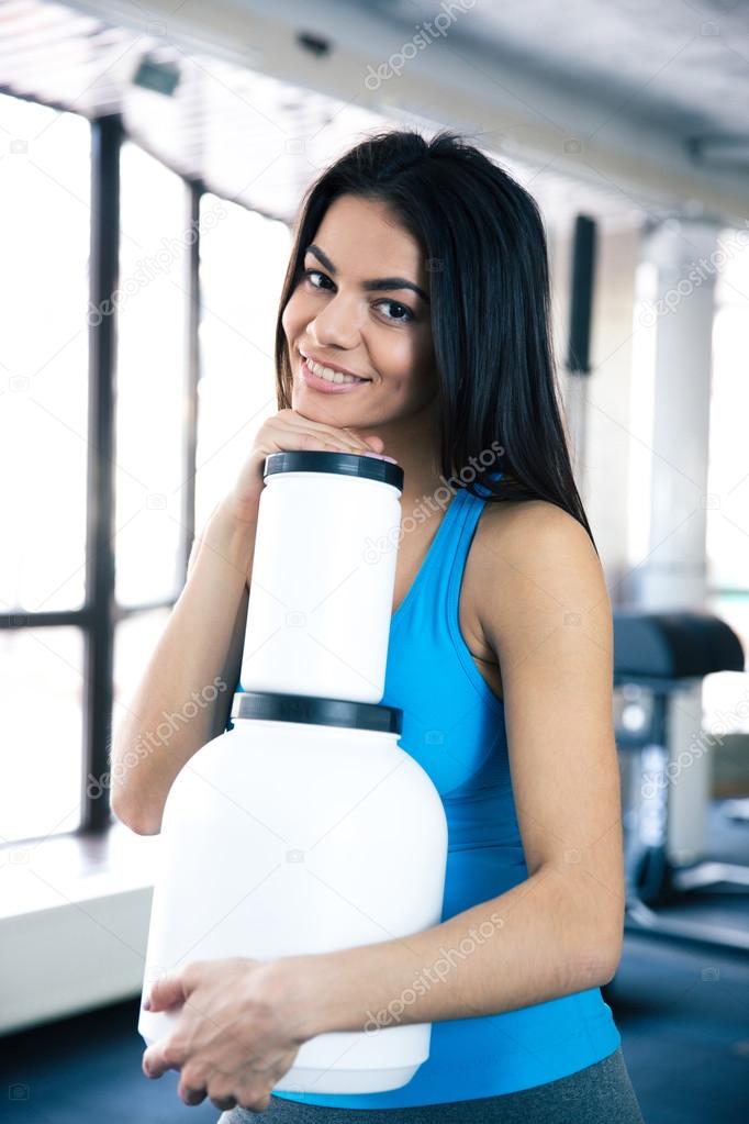 Smiling woman at gym with sports nutrition