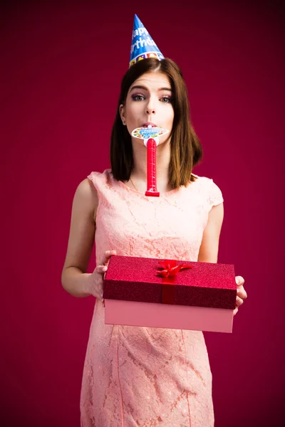 Mujer soplando en silbato y sosteniendo caja de regalo —  Fotos de Stock