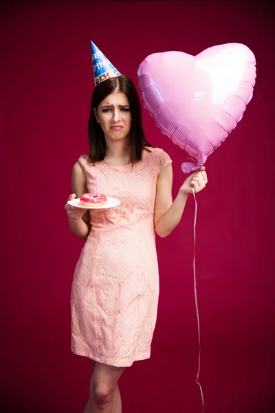 Woman holding heart shaped balloon and donut with candle — Stock Photo, Image