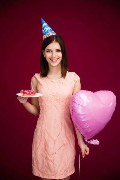 Woman holding heart shaped balloon and donut with candle — Stock Photo, Image