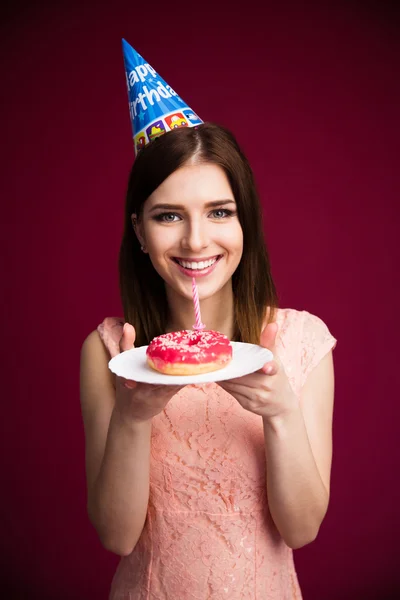 Smling young woman holding donut with candle — Stock Photo, Image