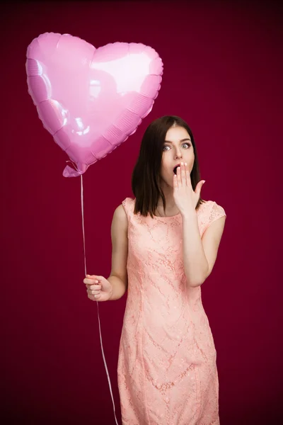 Young woman holding heart shaped balloon and yawning — Stock Photo, Image