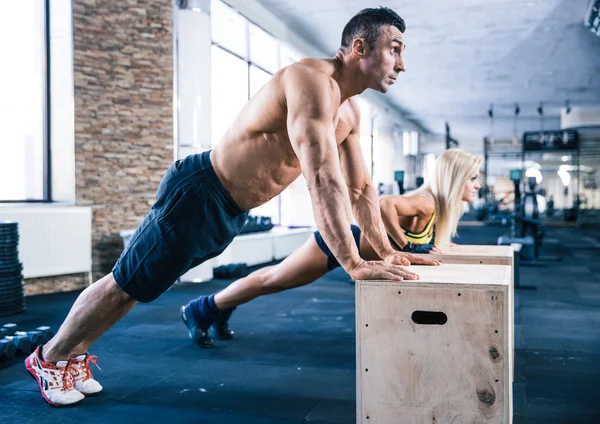Vrouw en man doet push ups op sportschool — Stockfoto
