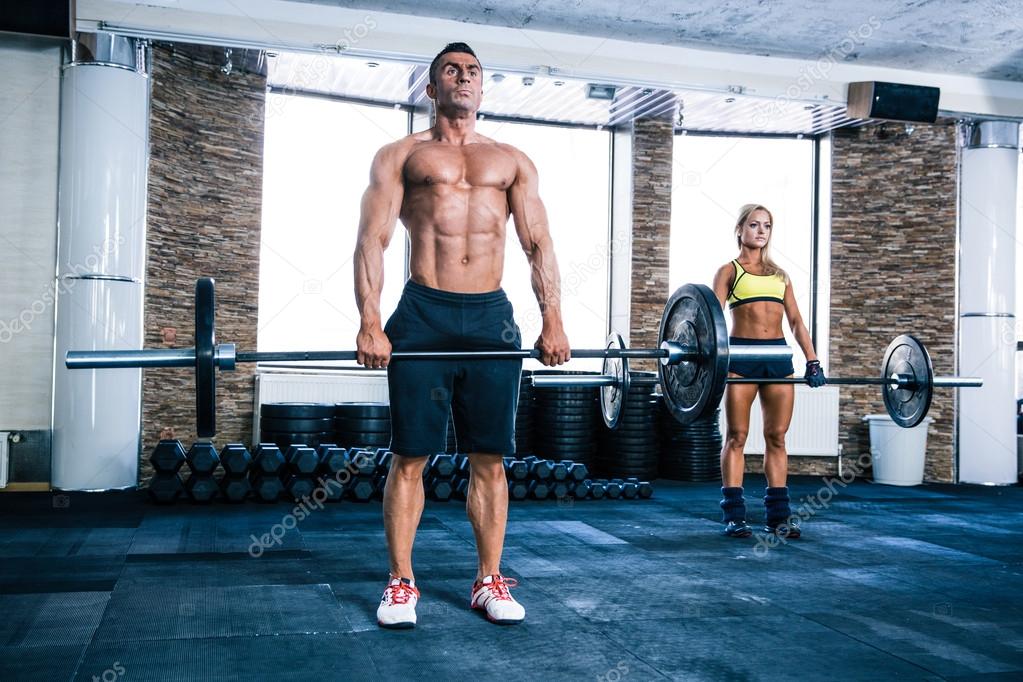 Muscular man and woman workout with barbell