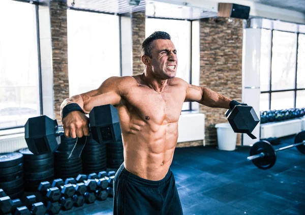 Muscular man lifting dumbbells — Stock Photo, Image