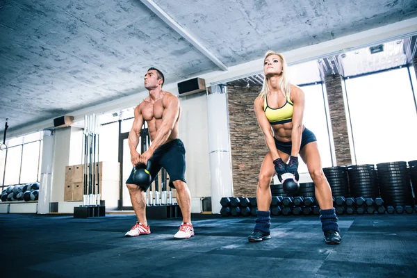 Musculoso hombre y la mujer en forma de bola hervidor de agua de elevación — Foto de Stock