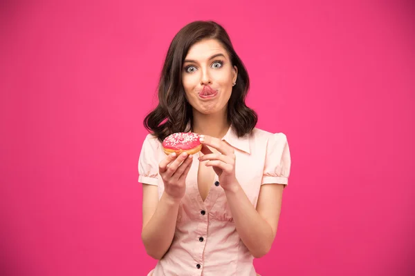 Молодая женщина держит пончик и показывает свой язык — стоковое фото