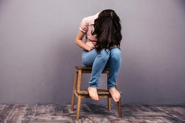 Jovem mulher sentada na cadeira em estúdio — Fotografia de Stock