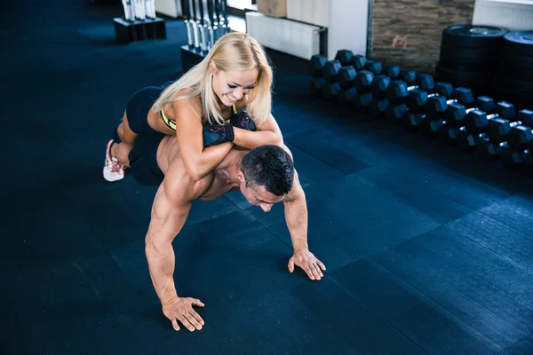 Muscular man doing push ups with woman on back — Stock Photo, Image