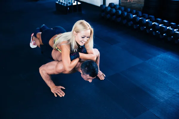 Homem muscular fazendo flexões com a mulher nas costas — Fotografia de Stock