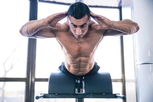 Homem muscular flexionando os músculos das costas no banco — Fotografia de Stock