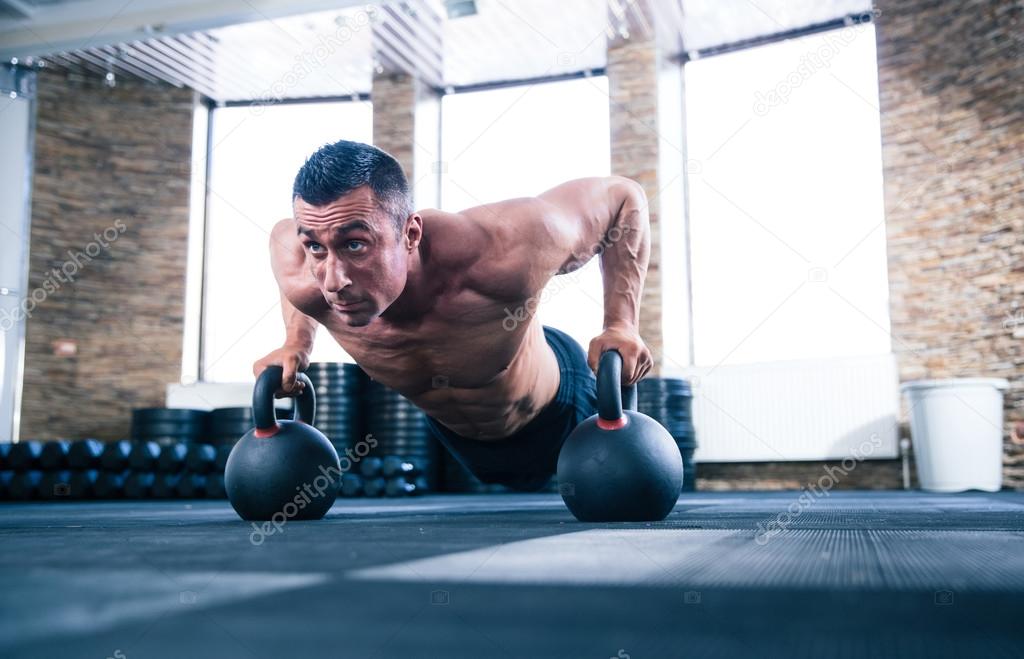Muscular man doing push ups in gym