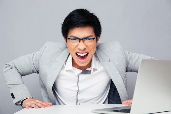 Joven enojado sentado a la mesa — Foto de Stock