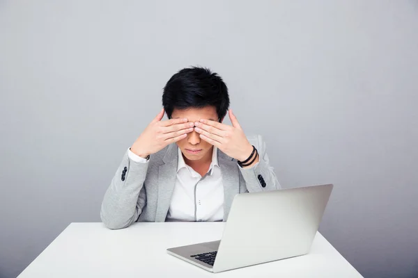 Businessman sitting at the table and covering his eyes — Stock Photo, Image