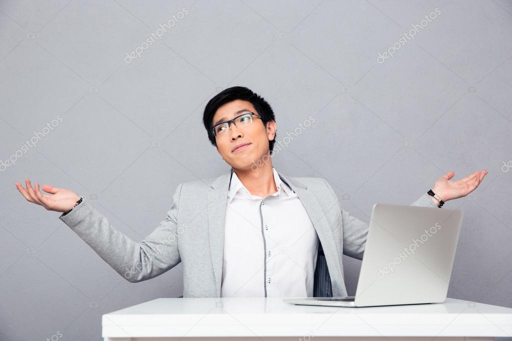 Businessman sitting at the table and shrugging
