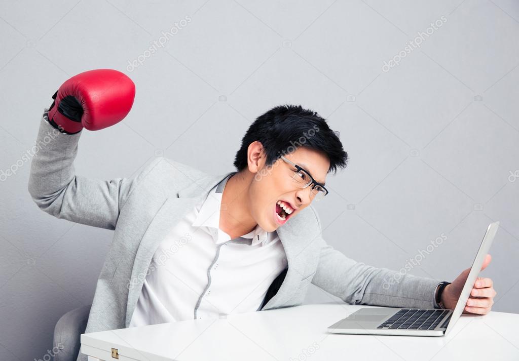 Angry businessman reading to hit the laptop