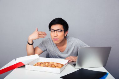 Masada oturan ve pizza kokulu aç genç adam