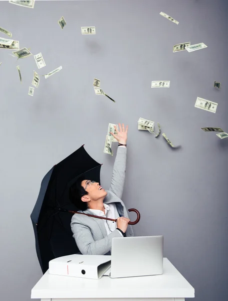 Businessman sitting at the table with rain of money — Stock Photo, Image