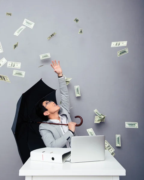 Geschäftsmann sitzt mit Geldregen am Tisch — Stockfoto