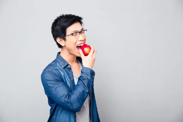 Joven asiático hombre mordiendo rojo manzana —  Fotos de Stock