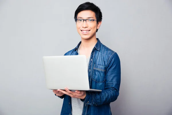 Alegre asiático hombre de pie con laptop — Foto de Stock