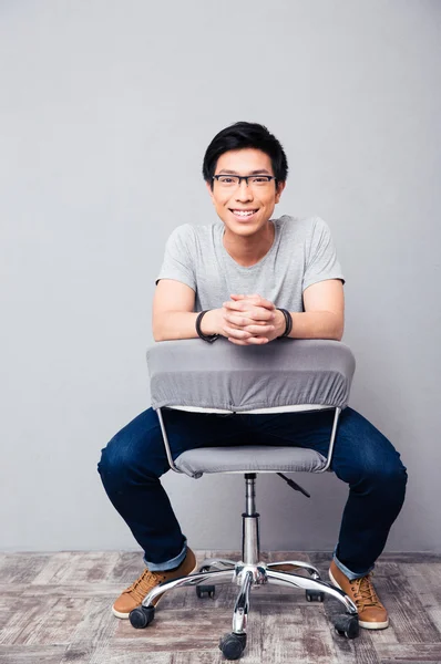 Sandalyede oturan neşeli Asyalı adam — Stok fotoğraf