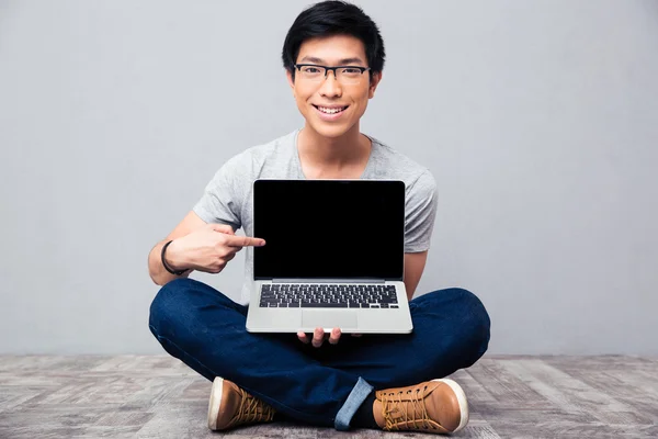 Lächelnder Asiate zeigt Finger auf Laptop-Bildschirm — Stockfoto