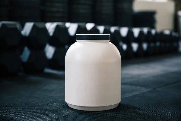 Plastic container with sports nutrition on dumbbells