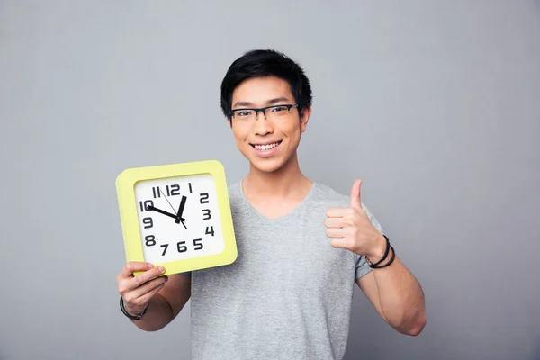Feliz asiático hombre celebración Grande reloj y mostrando pulgar arriba — Foto de Stock