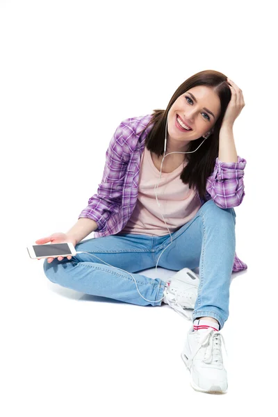 Sorrindo jovem sentada no chão com smartphone — Fotografia de Stock