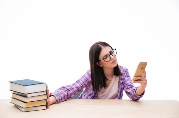 Студентка толкает книги и использует смартфон — стоковое фото