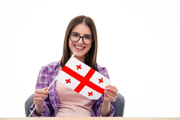 Mujer feliz en gafas sentada a la mesa con bandera de Georgia —  Fotos de Stock