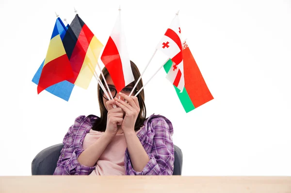 Mujer joven sentada a la mesa con banderas internacionales —  Fotos de Stock
