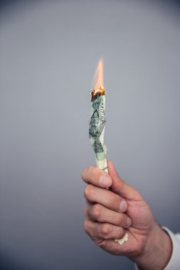 Bize yanan bir dolarlık banknot tutan erkek el 