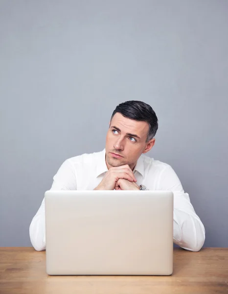 Empresário atencioso sentado à mesa com laptop — Fotografia de Stock