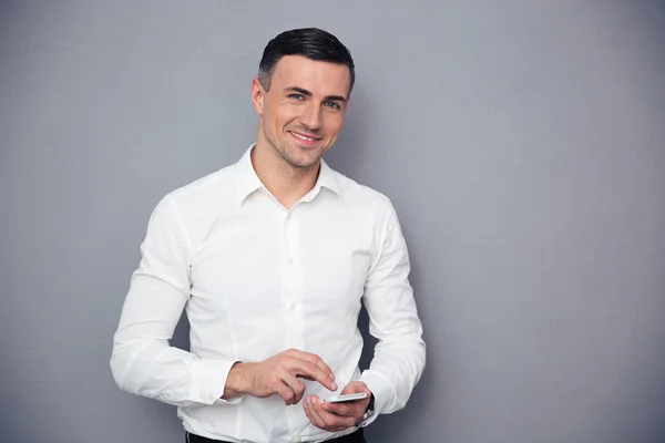 Geschäftsmann nutzt Smartphone vor grauem Hintergrund — Stockfoto