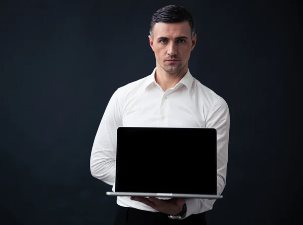 Uomo d'affari che mostra lo schermo del computer portatile vuoto — Foto Stock