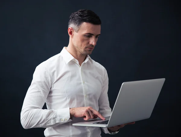 Empresario de pie y utilizando el ordenador portátil — Foto de Stock