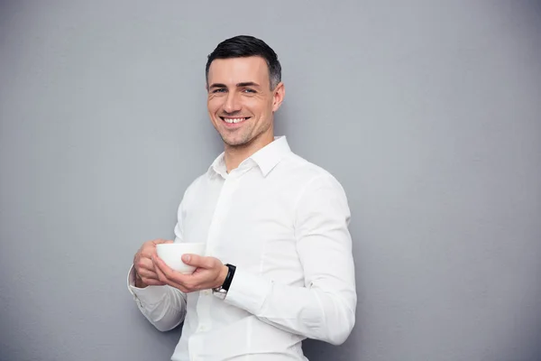 Cheerful young businessman holding cup of coffee — Stock Photo, Image