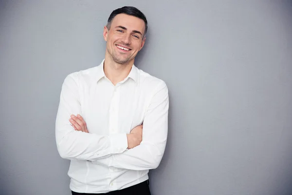 Hombre de negocios sonriente de pie con los brazos cruzados — Foto de Stock