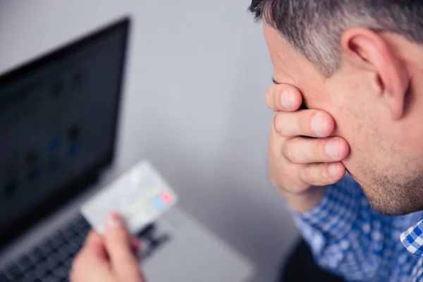 Homem perturbado segurando cartão de crédito — Fotografia de Stock