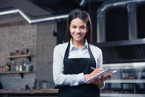 Charming female waiter in apron writing order — Stock Photo, Image