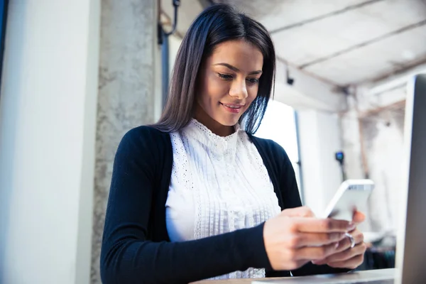 Mujer de negocios sonriente usando teléfono inteligente en la cafetería — Foto de Stock