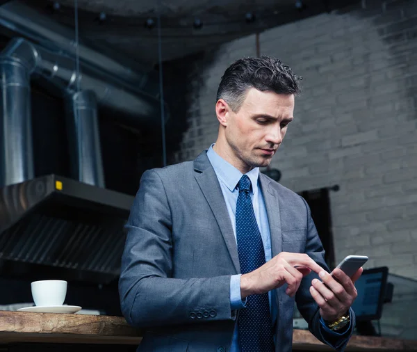 Hombre de negocios con teléfono inteligente en la cafetería — Foto de Stock