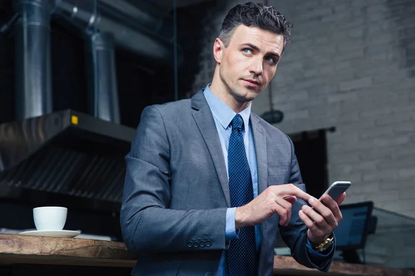 Fundersam affärsman med smartphone i café — Stockfoto