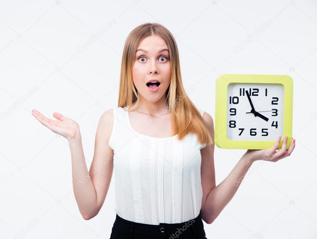 Surprised young woman holding big clock