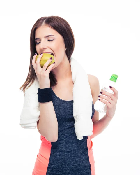 Fitness woman eating apple and holding bottle with water — Stock Photo, Image