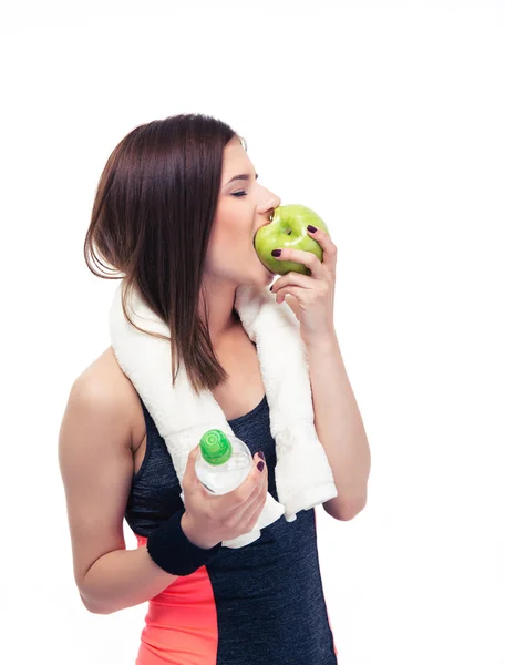 Sporty woman eating apple and holding bottle with water — Stock Photo, Image