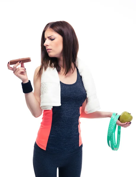 Спортивная женщина делает выбор между яблоком и шоколадом — стоковое фото